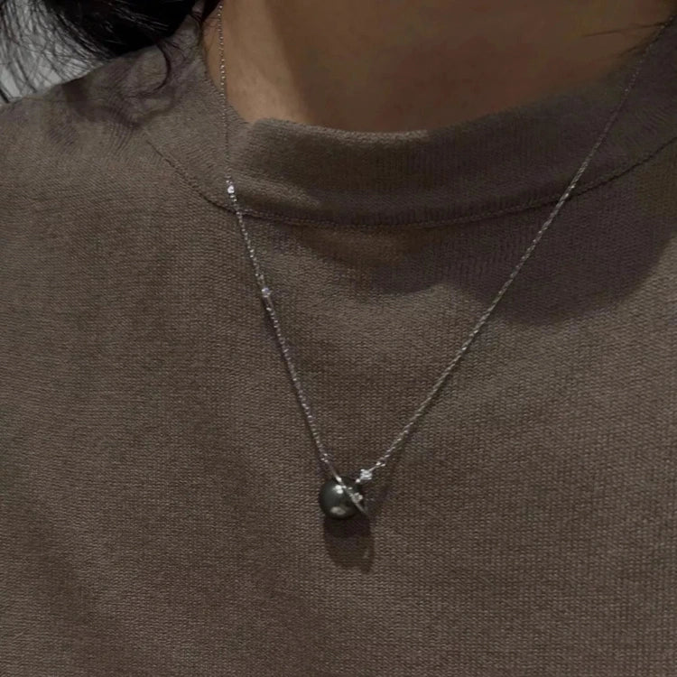 Pearl Planet Pendant Necklace worn on chest with brown ribbed-knit top
