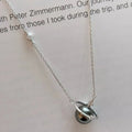 Flat lay of dark gray pearl planet pendant necklace with clear gemstone accents