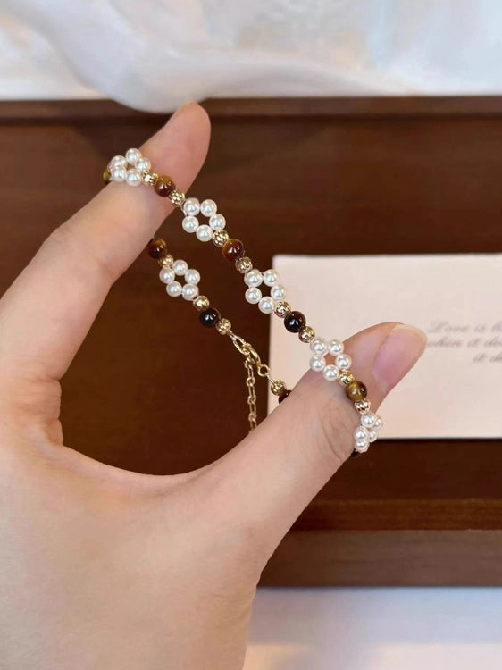 Hand holding a pearl bracelet with a blurred background