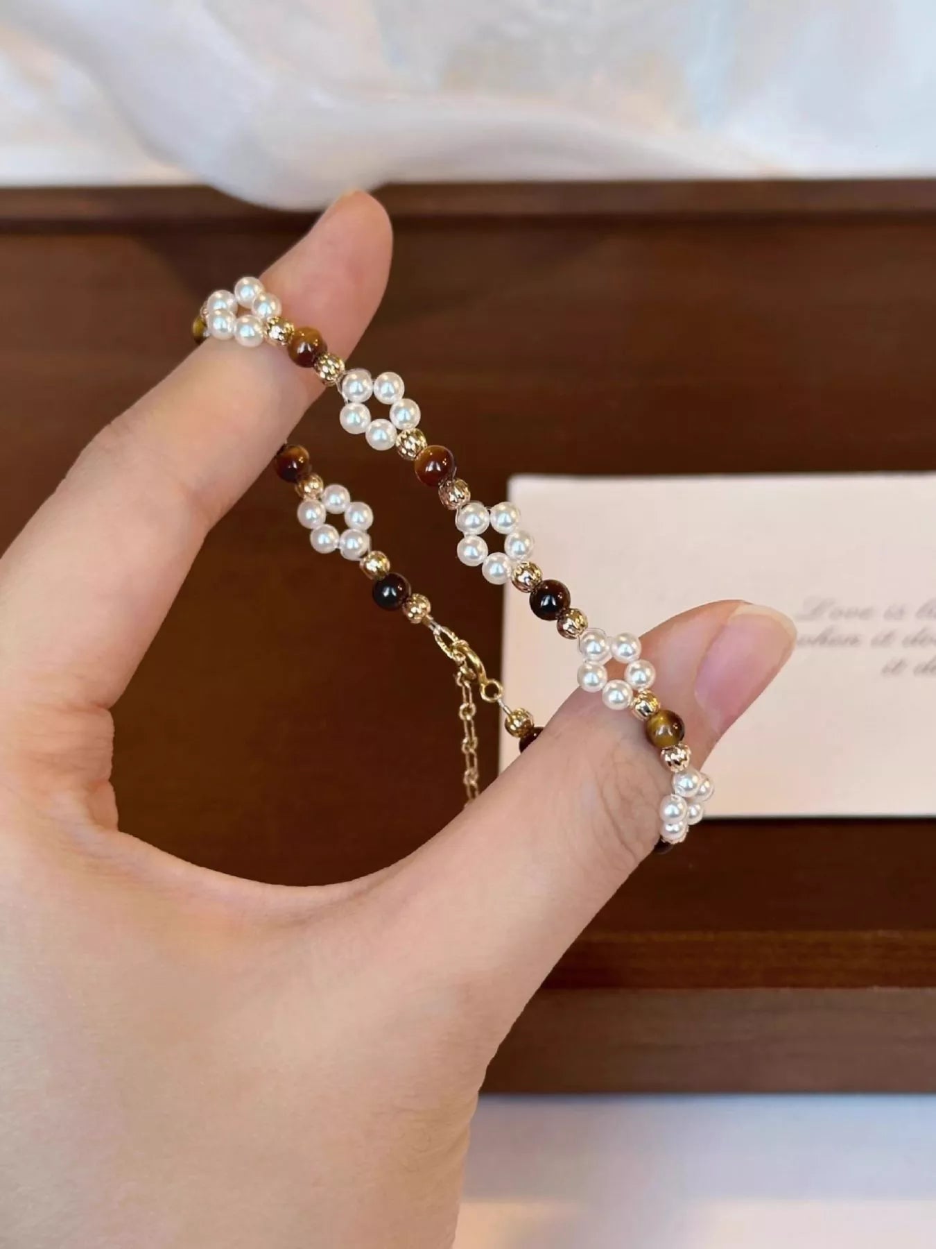 Hand holding a pearl bracelet with a blurred background