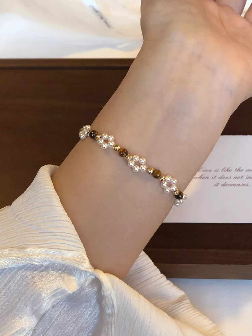 Close-up of a wrist wearing a beaded bracelet with a neutral background