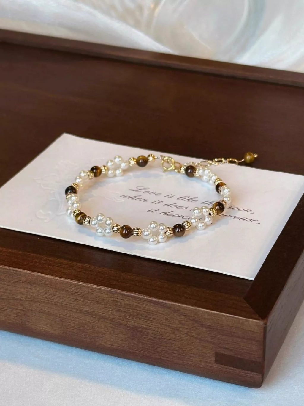 Pearl and brown beaded bracelet on a wooden box with a message card.