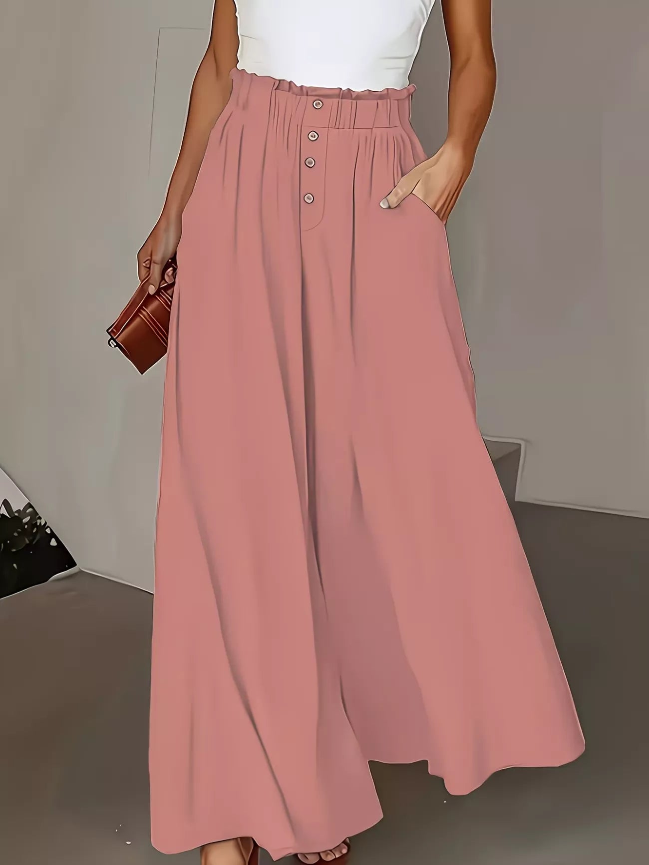 Person wearing a long pink wide leg pants with a plain background