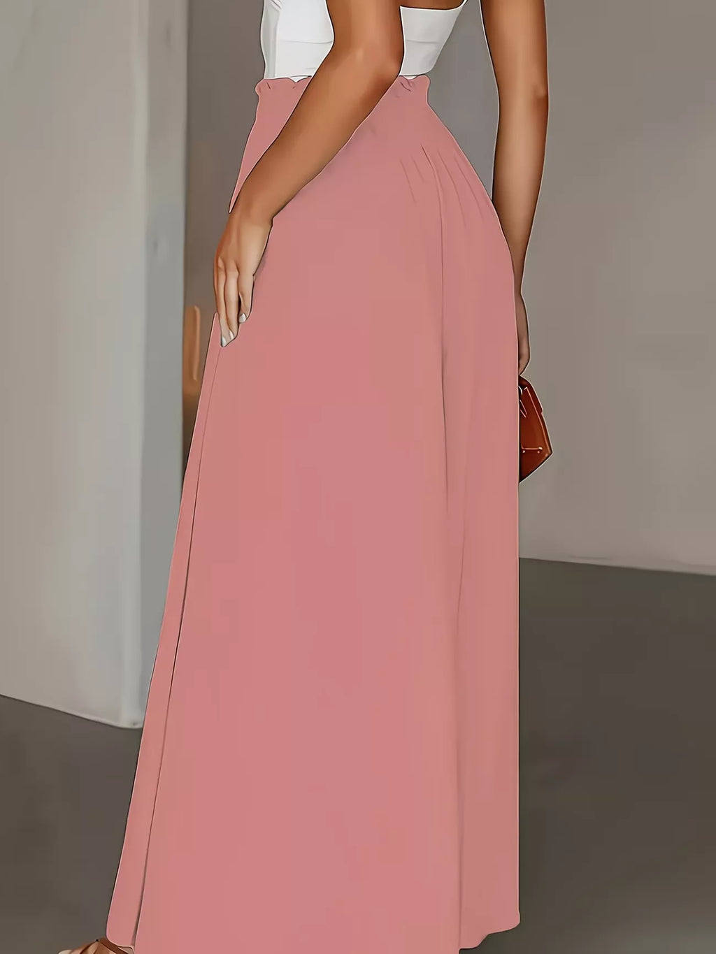 Person wearing a long pink skirtwide leg pants with a neutral background