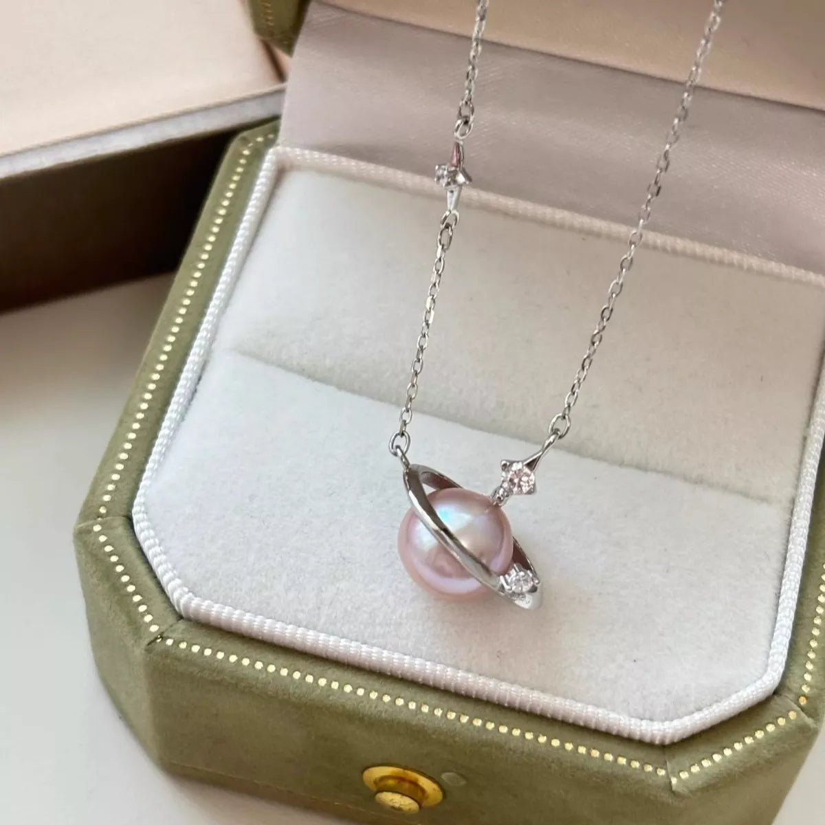 Necklace with a pink pearl pendant on a green jewelry box