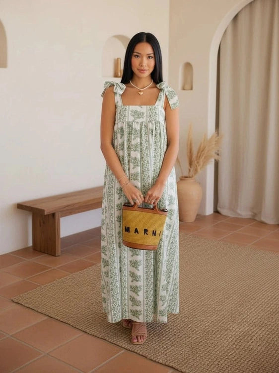 Woman in a green dress holding a brown bag with 'Marni' branding in a living room.