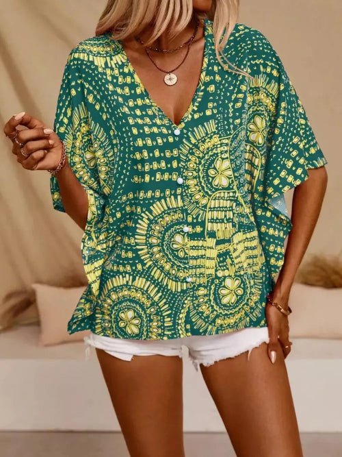 Woman wearing a green and yellow patterned top with white shorts indoors.