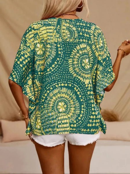 Person wearing a green and yellow patterned top with white shorts on a beige background