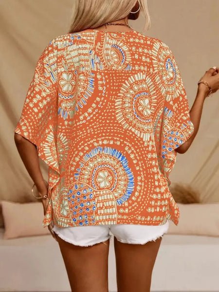 Woman wearing an orange patterned kimono-style top with white shorts against a beige background
