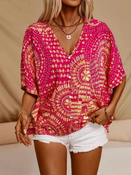 Person wearing a vibrant pink and red patterned top with white shorts against a neutral background