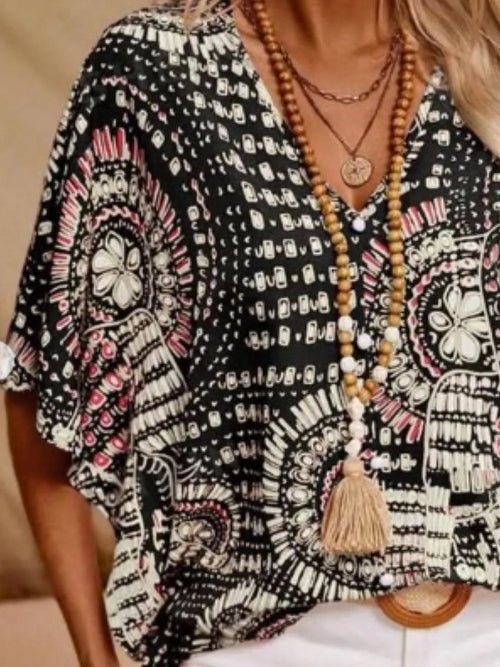 Person wearing a black patterned kimono with a long necklace featuring tassels.