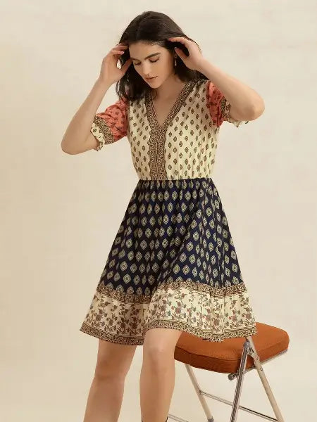 Woman wearing a patterned dress sitting on a chair against a plain background