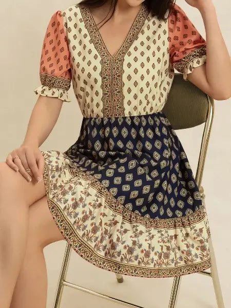 Woman wearing a patterned dress sitting on a chair.