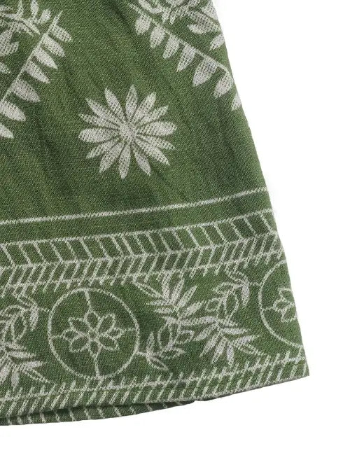 Green fabric with white floral and geometric patterns on a white background