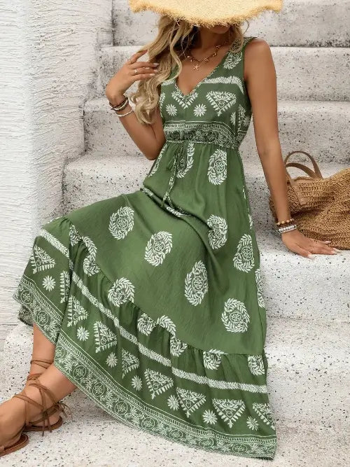 Woman wearing a green dress with white patterns sitting on stairs.