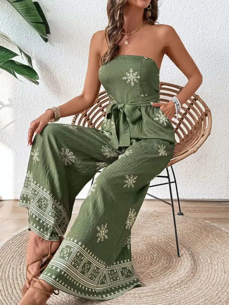 Woman wearing a green strapless jumpsuit with floral patterns sitting on a chair.