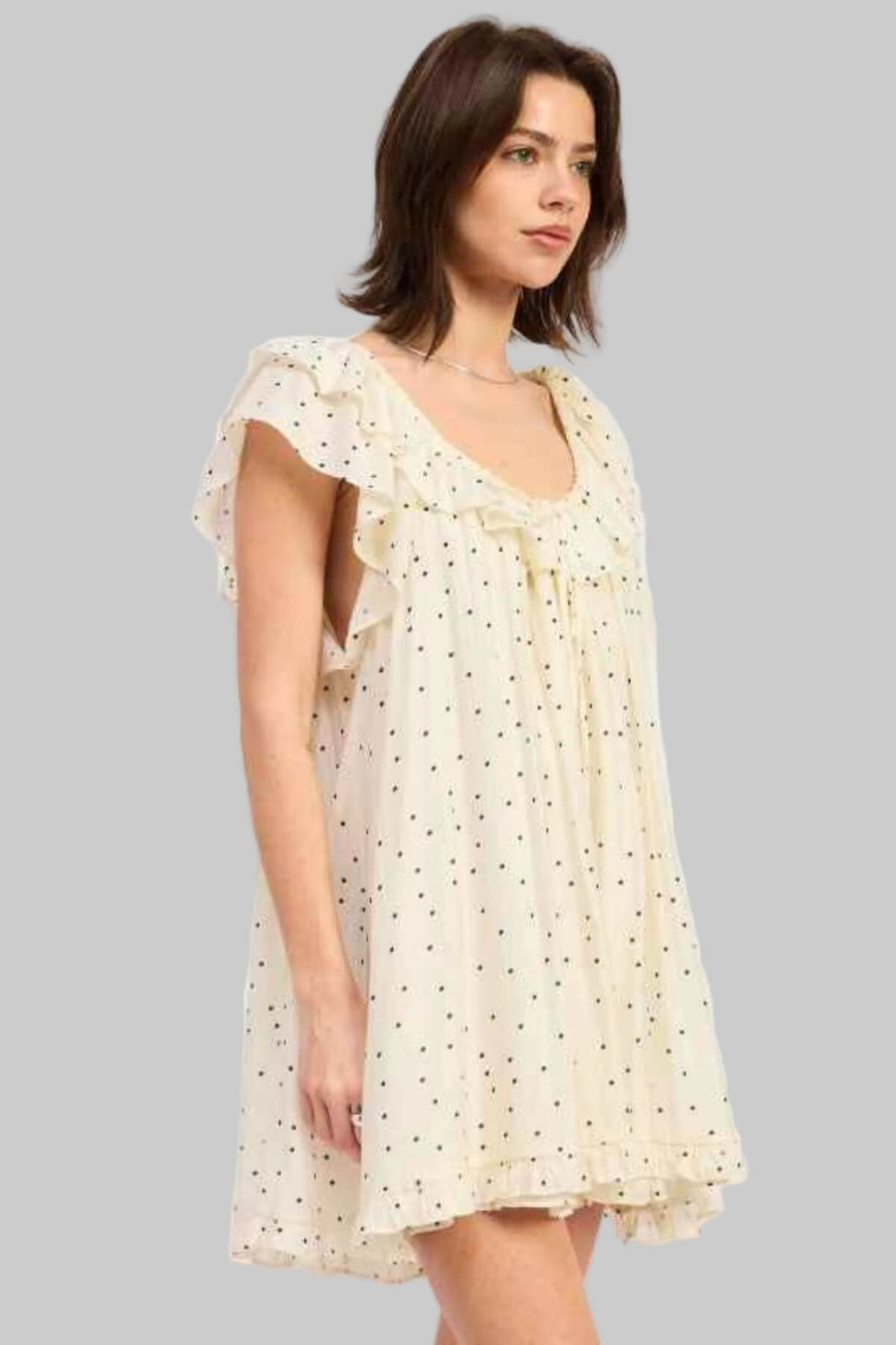 Woman wearing a light yellow dress with ruffled sleeves on a white background