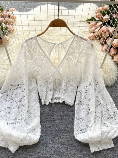 White lace top on a hanger with floral decorations in the background