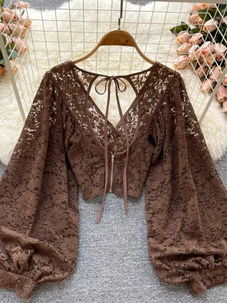 Brown lace top on a hanger with a floral background