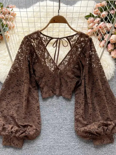 Brown lace top on a hanger with floral decorations in the background