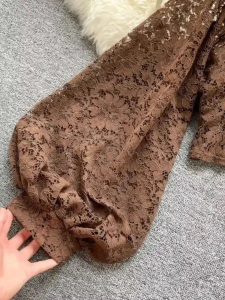Brown lace fabric on a gray surface with a hand touching it