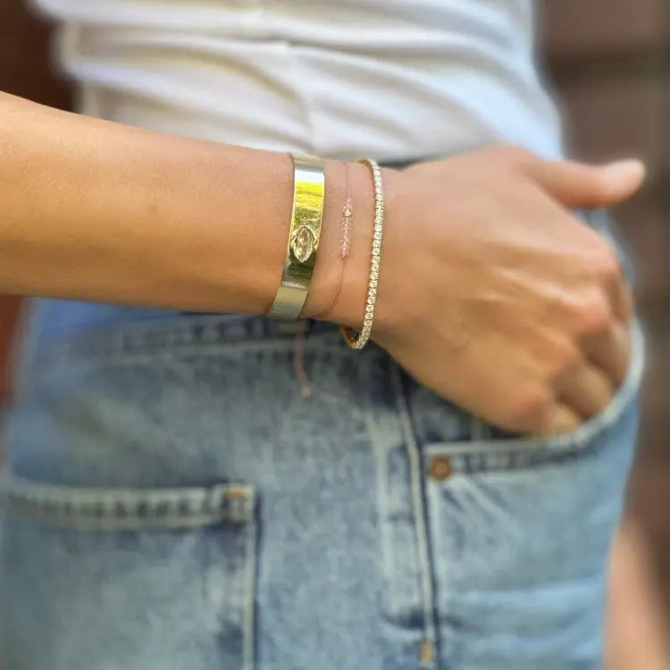 Close-up of a person's wrist wearing gold and silver bracelets with a blurred background.
