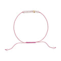 Pink bracelet with a small gold charm on a white background
