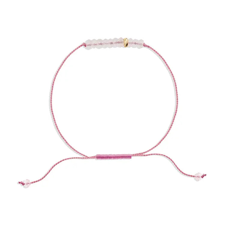 Pink bracelet with a small gold charm on a white background