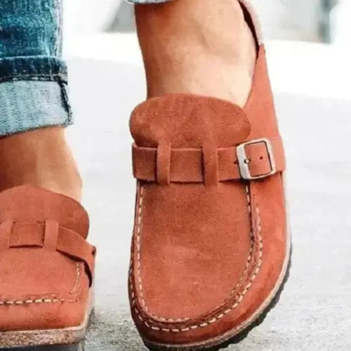Brown suede loafers with a buckle on a light background