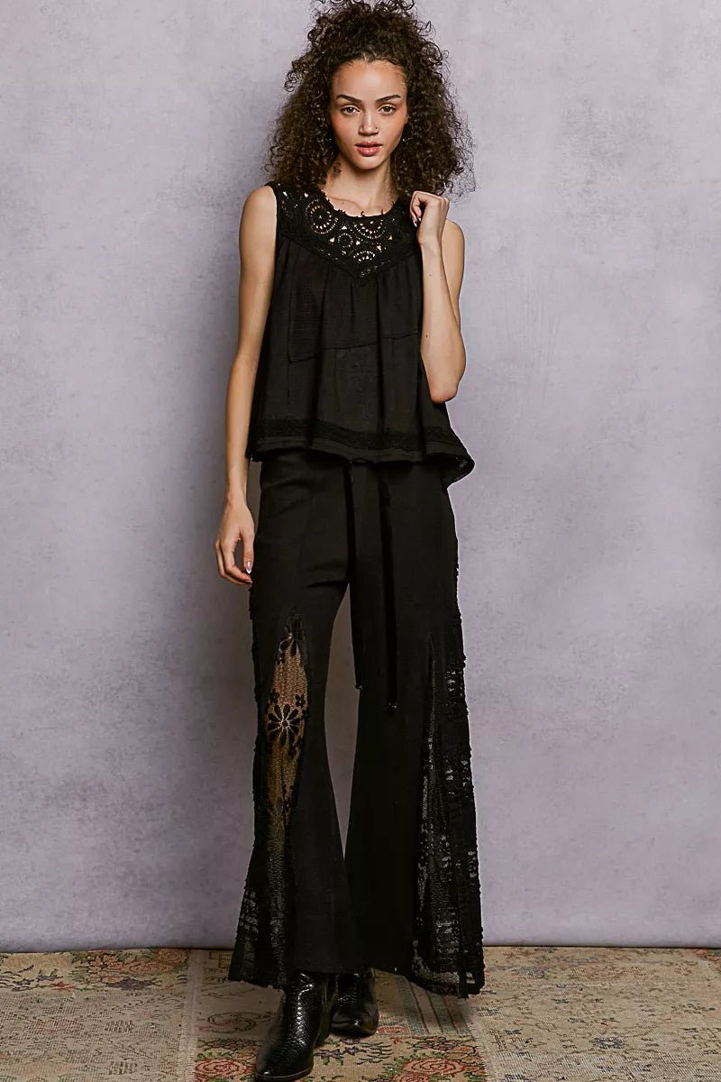 Woman wearing a black outfit with lace details against a plain background