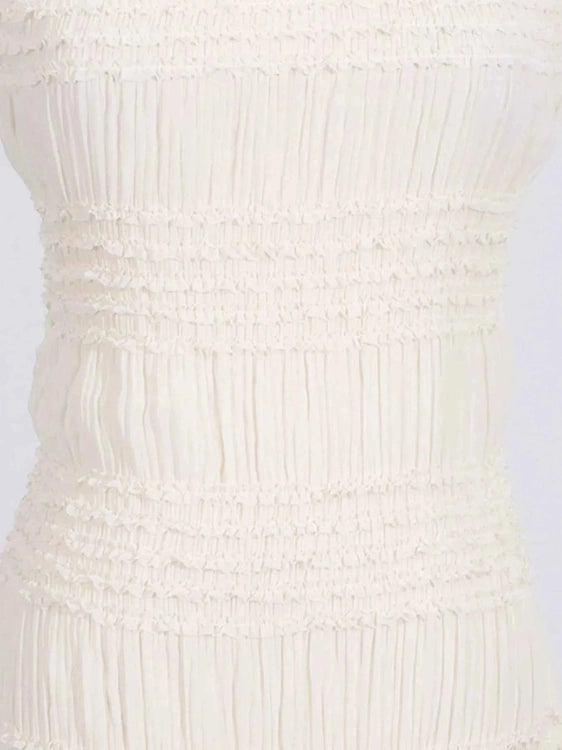 Close-up of a textured white dress on a light gray background