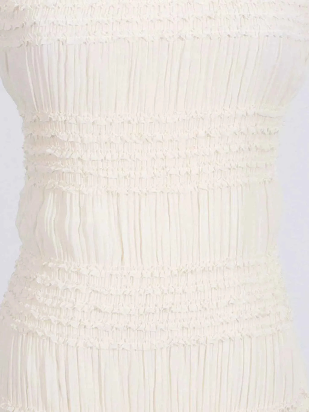 Close-up of a textured white dress on a light gray background