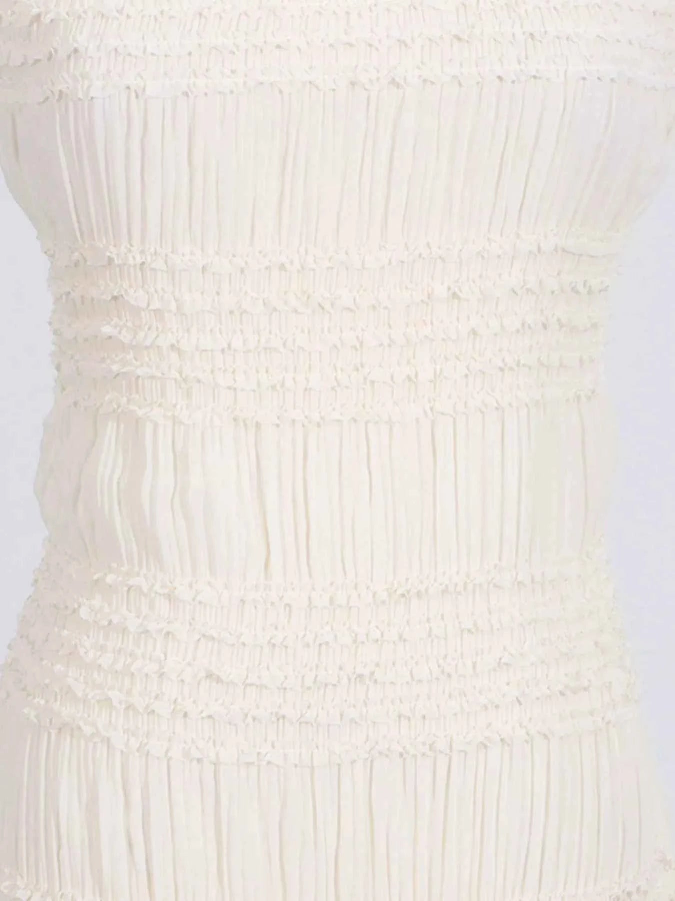 Close-up of a textured white dress on a light gray background