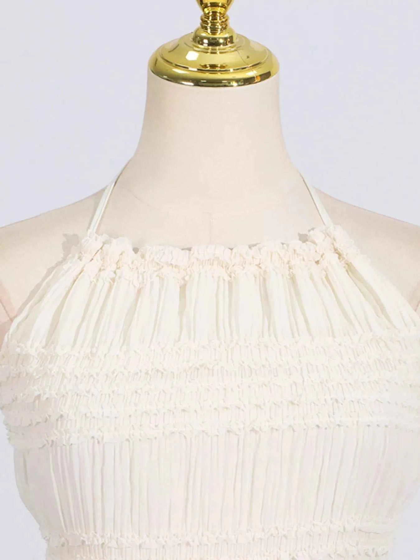 White dress on a mannequin with a gold top against a white background