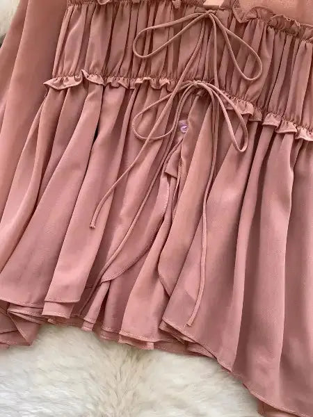 Close-up of a brown shirt with ruffled layers on a white fur surface
