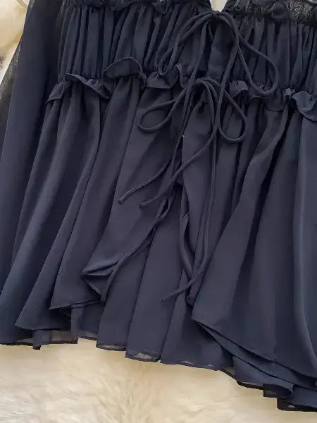 Navy blue lace-trimmed dress on a textured beige surface
