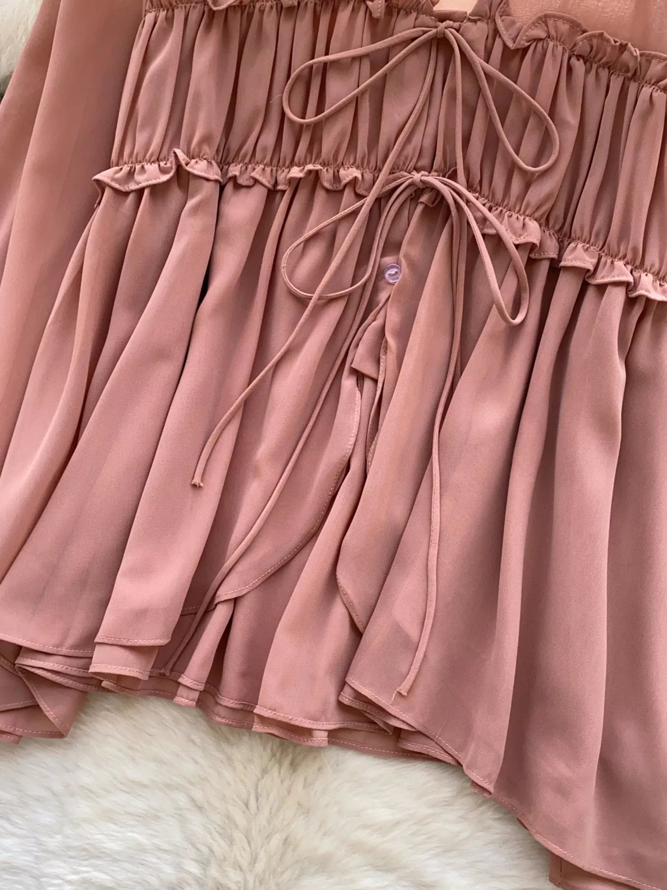 Close-up of a brown shirt with ruffled layers on a white fur surface