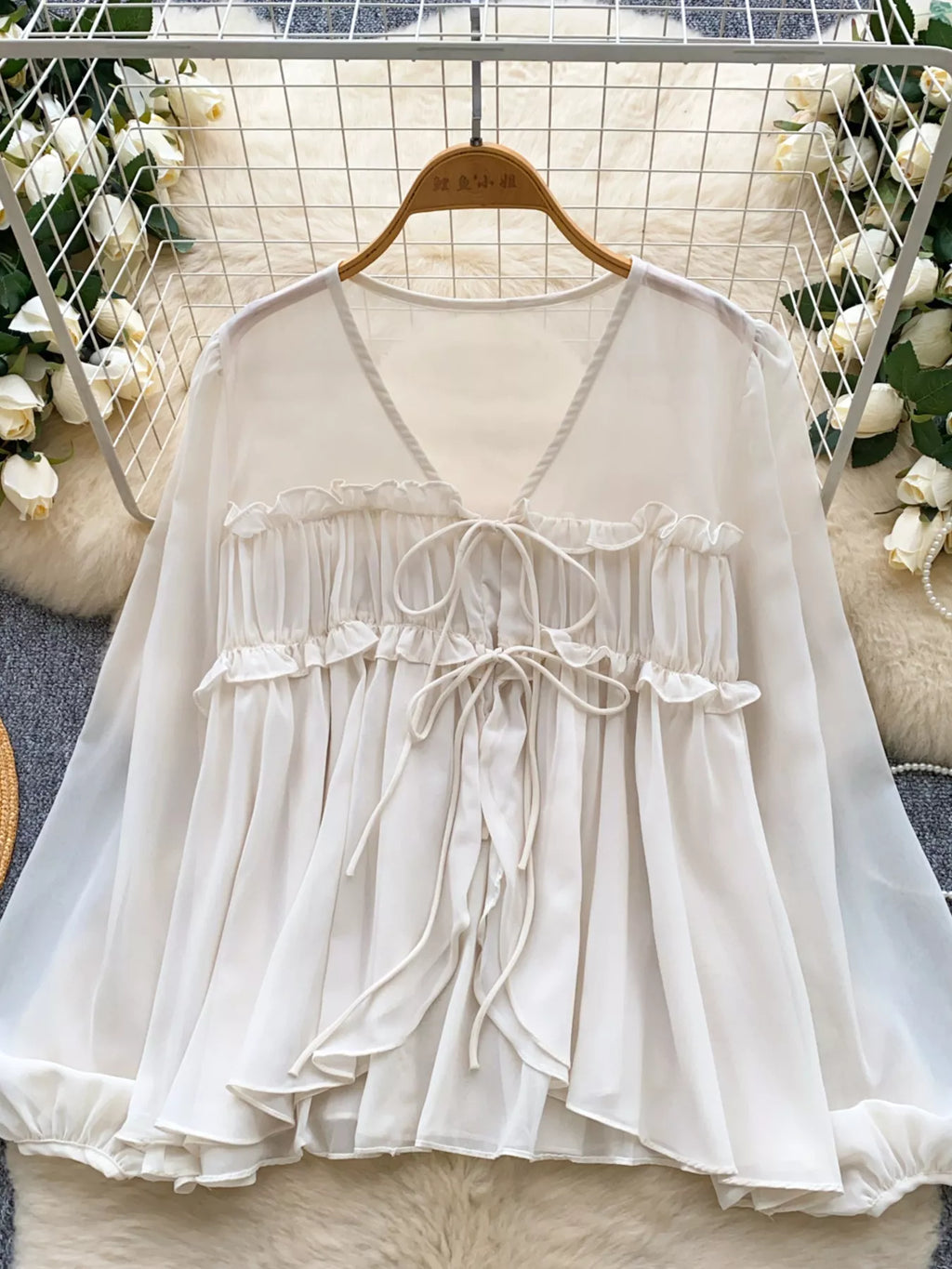 White lace top on a hanger with a floral background