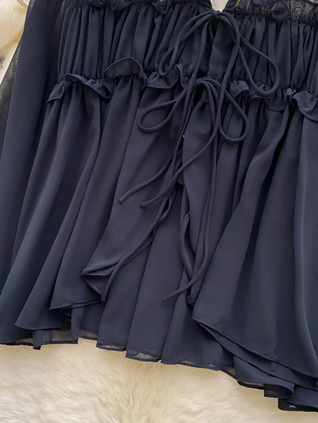 Navy blue lace-trimmed dress on a textured beige surface