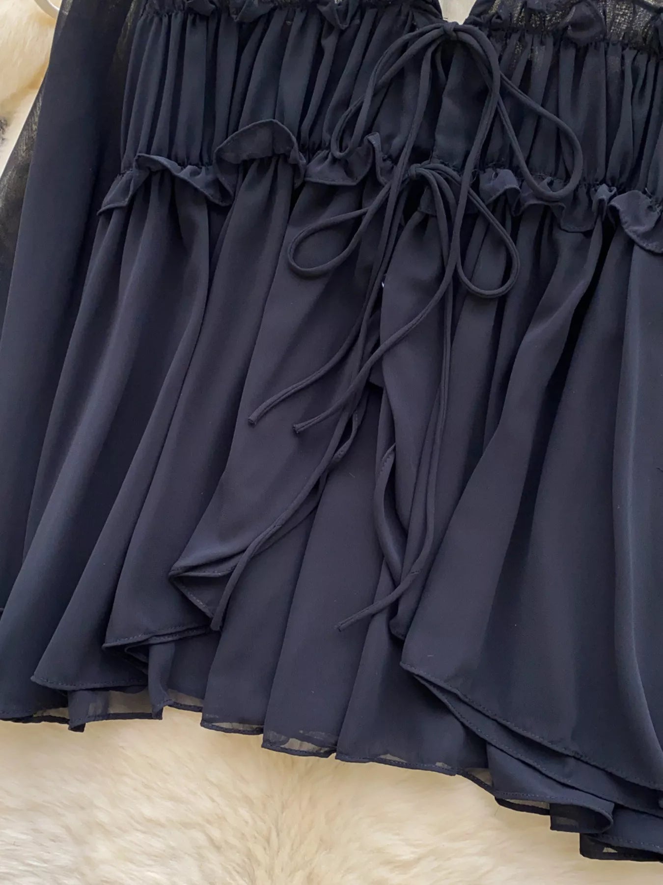 Navy blue lace-trimmed dress on a textured beige surface