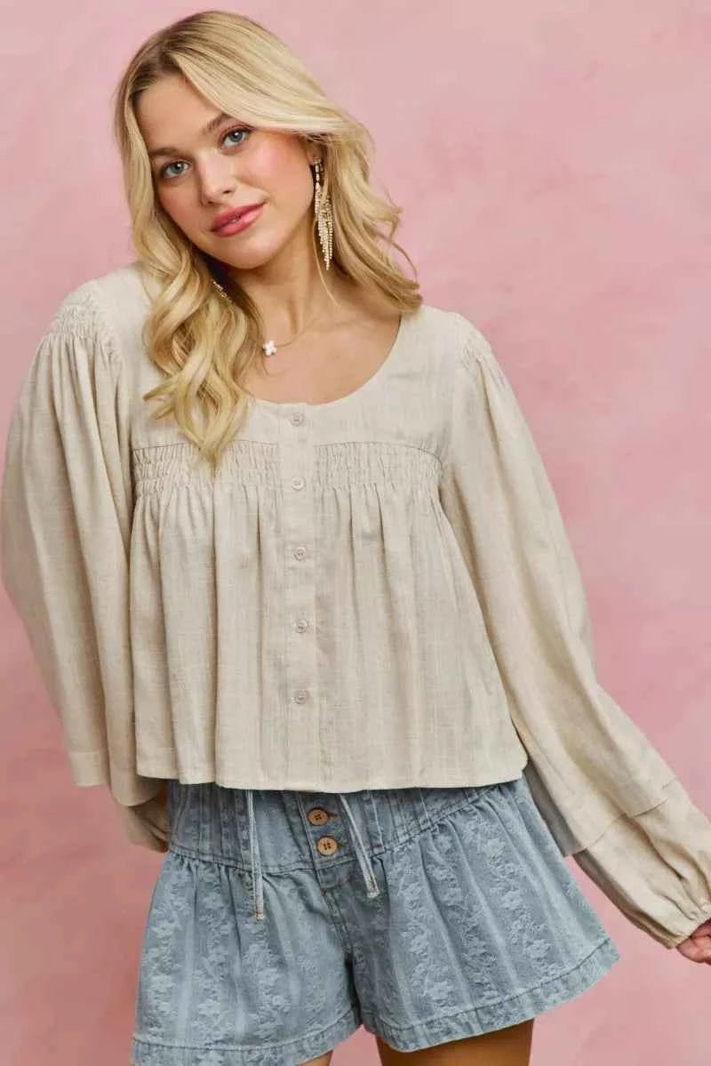 Woman wearing a beige blouse and denim shorts against a pink background