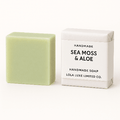 Bar of sea moss and aloe handmade soap next to its packaging on a white background