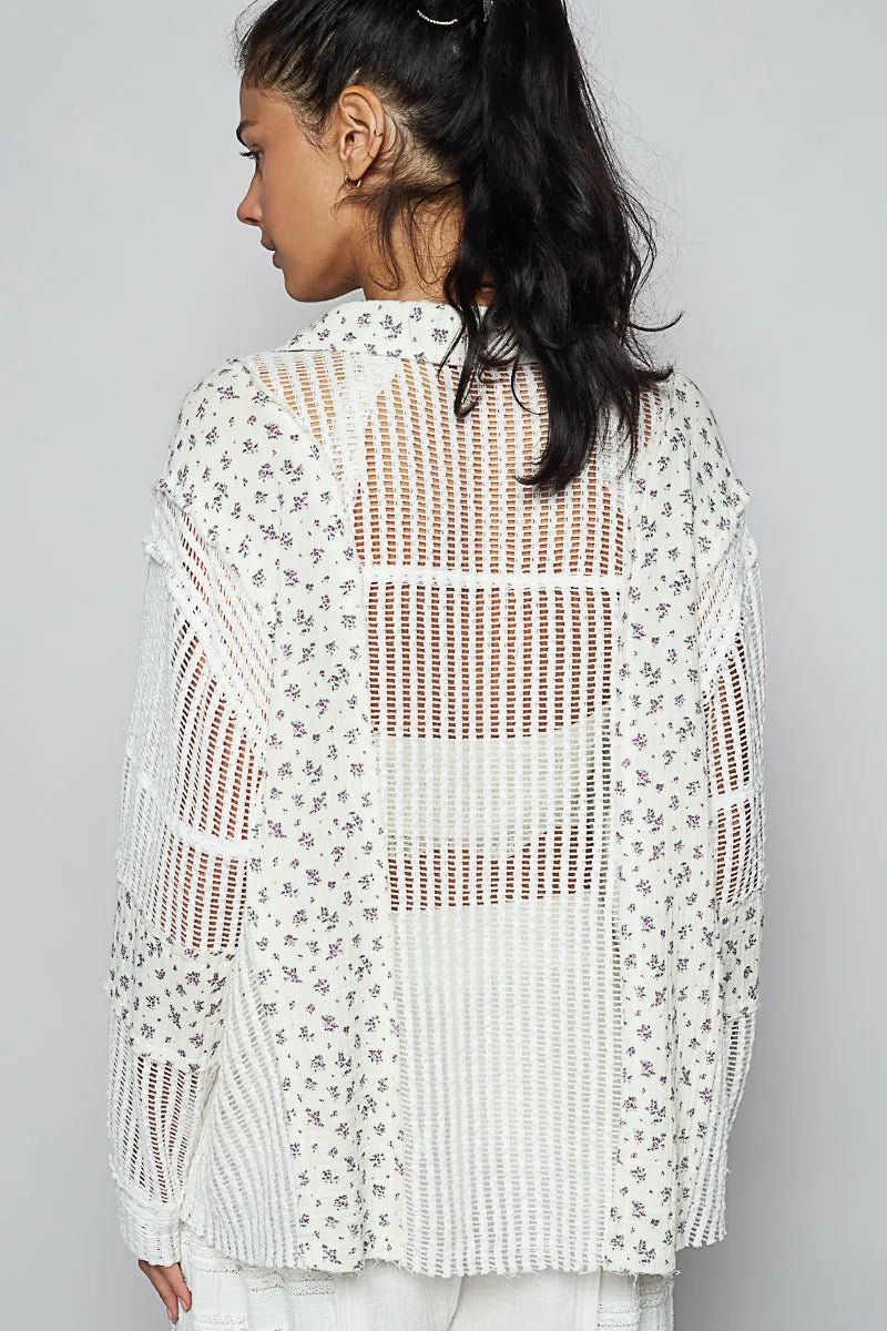 Woman wearing a white crochet top with floral patterns on a gray background