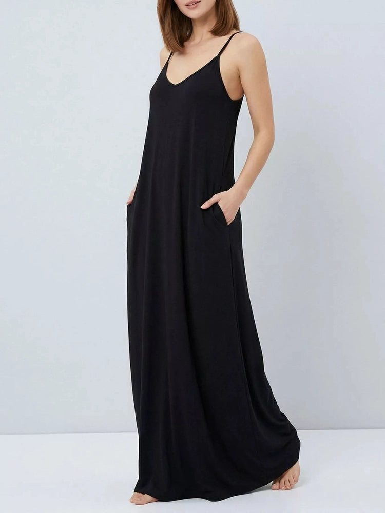 Woman wearing a black slip dress against a plain background