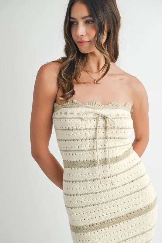 Woman wearing a beige crochet strapless dress against a white background