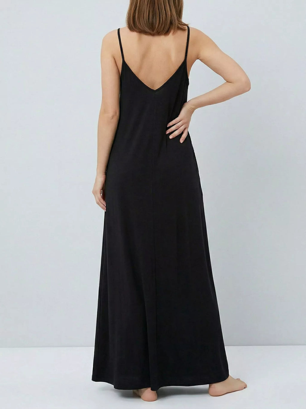 Woman wearing a black slip dress against a plain background