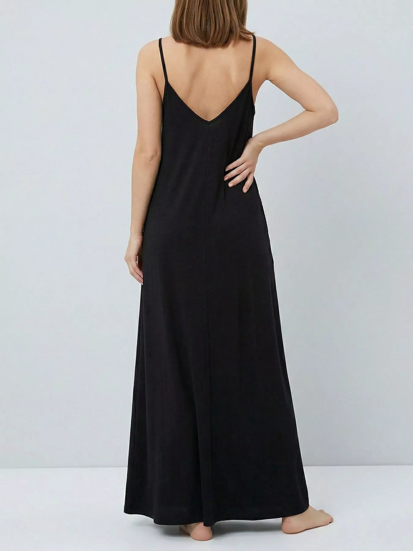 Woman wearing a black slip dress against a plain background