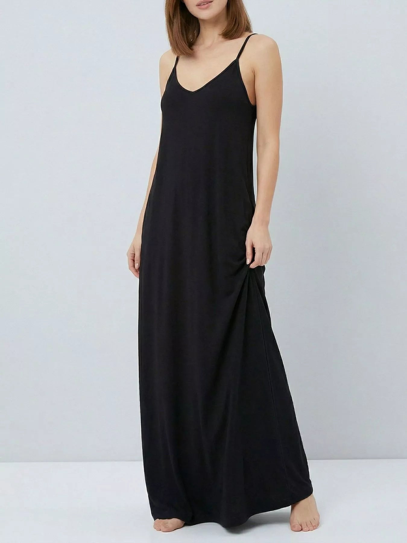 Woman wearing a black slip dress against a plain background