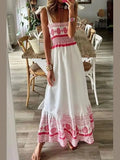 Woman wearing a white dress with red and pink patterns in a room with wooden flooring.