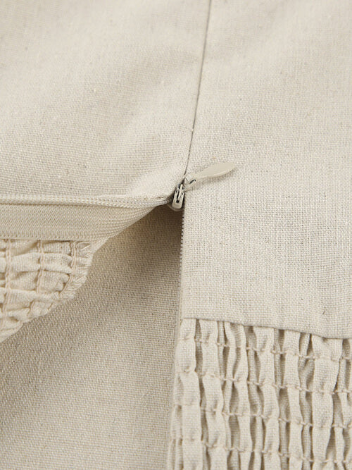 Close-up of a beige textured fabric with a zipper detail.